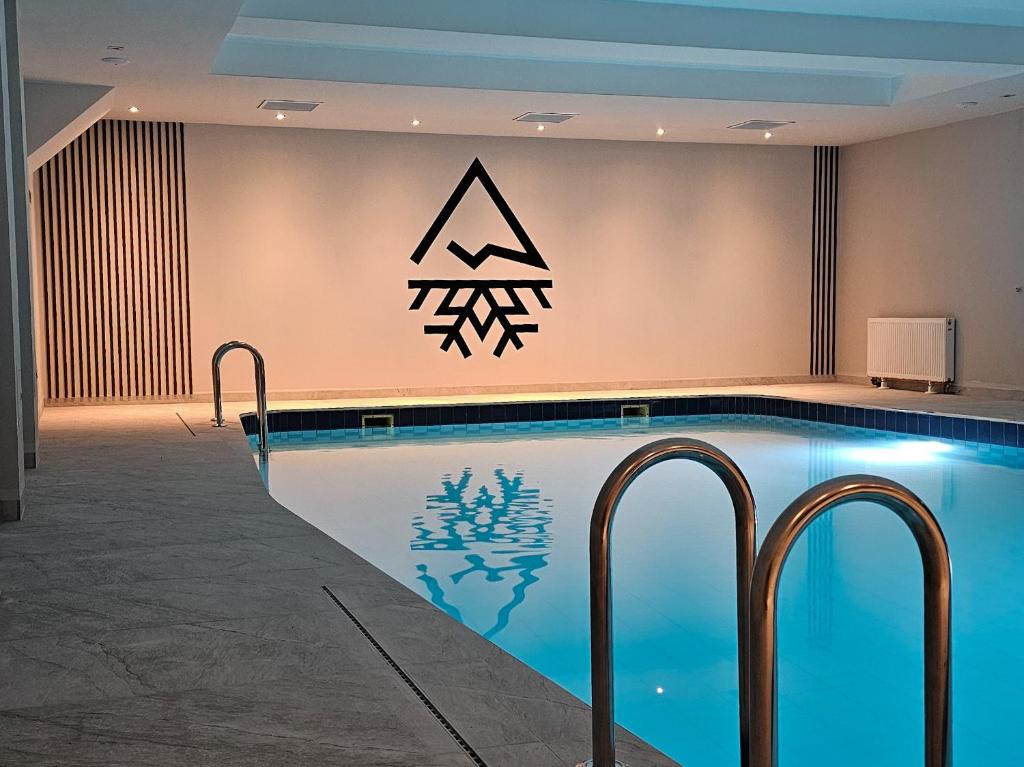 什切尔克Śnieżynka的墙上有标志的酒店游泳池