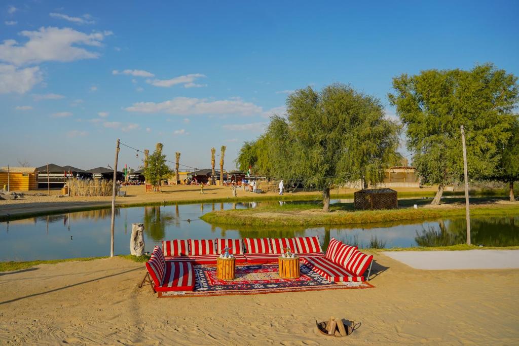 迪拜Al Marmoom Oasis “Luxury Camping & Bedouin Experience”的公园里沙子上的红色沙发