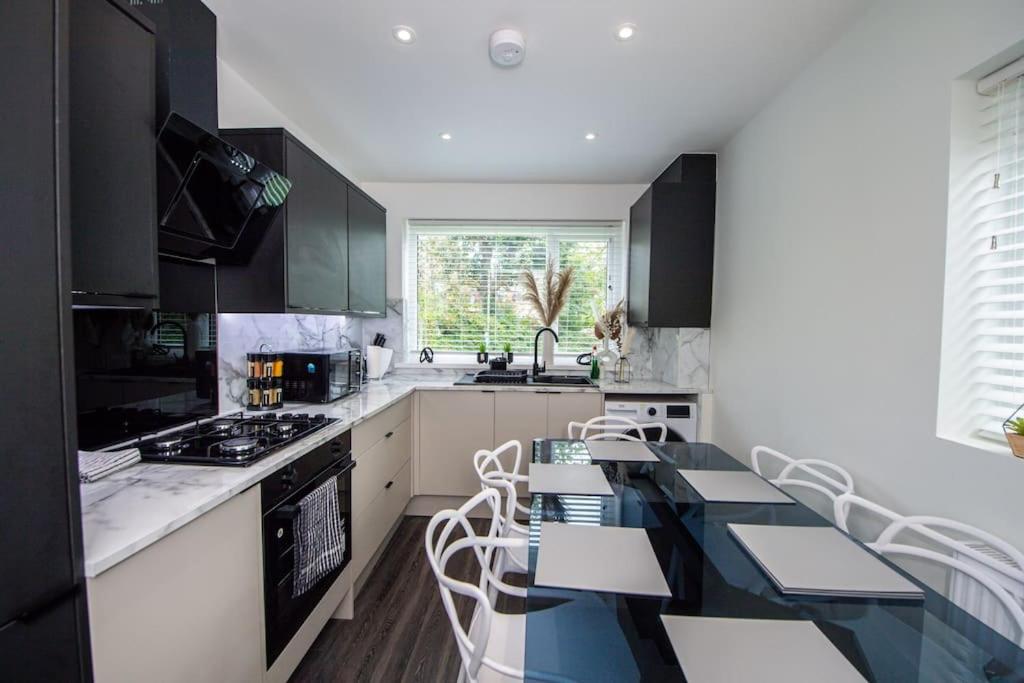 曼彻斯特Modern 4-Bed Retreat with Garden的厨房配有黑白橱柜和桌椅