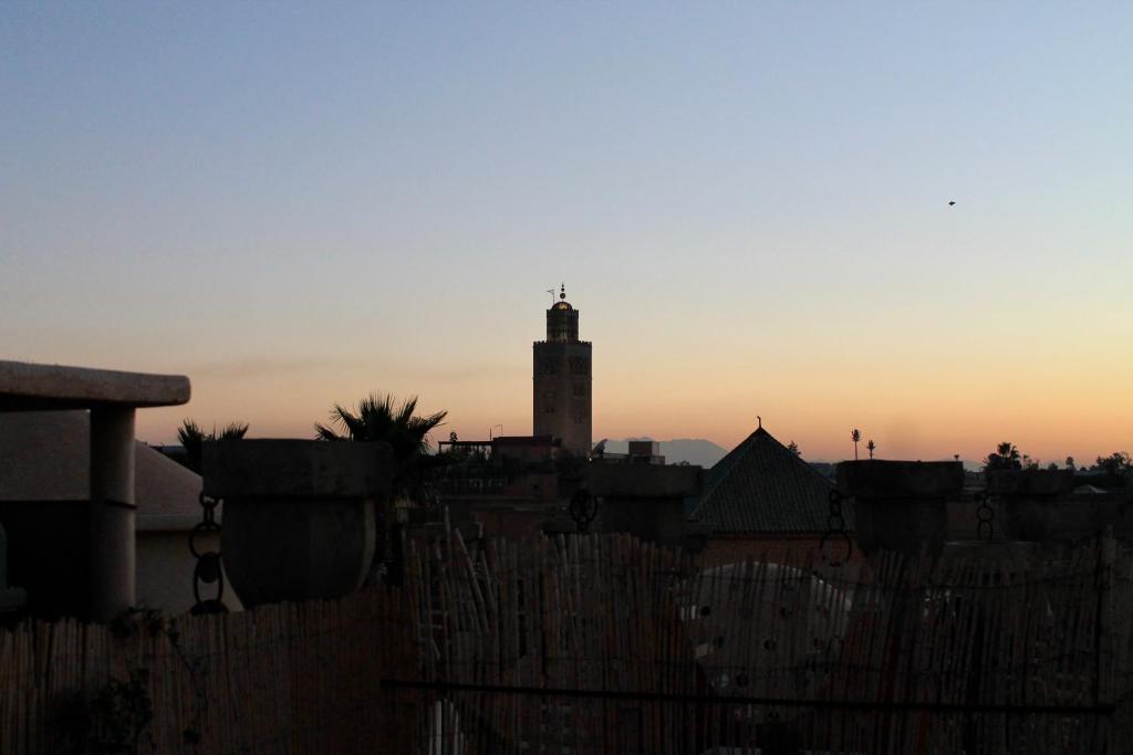 马拉喀什Hostel kif kif annex的落日时钟塔楼建筑的轮廓