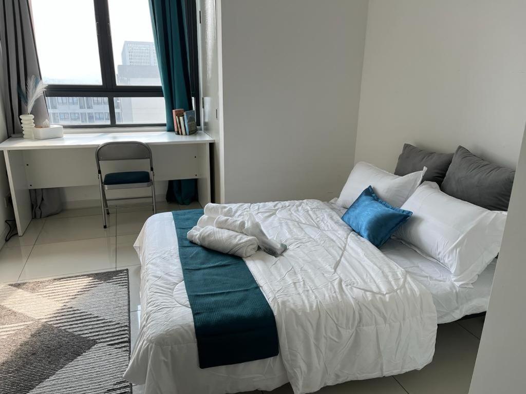 雪邦horizon suite 25-11的一间卧室配有一张带蓝色枕头的床和一张书桌