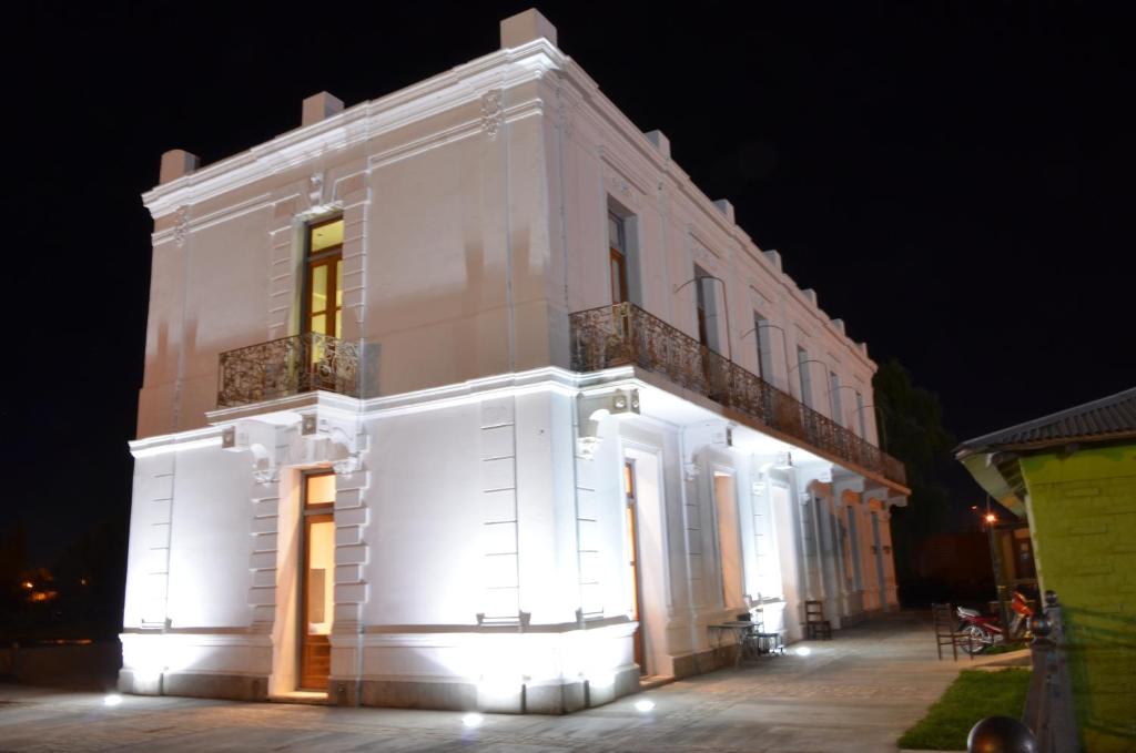 罗卡将军市Hotel El Recreo的白色的建筑,晚上有灯
