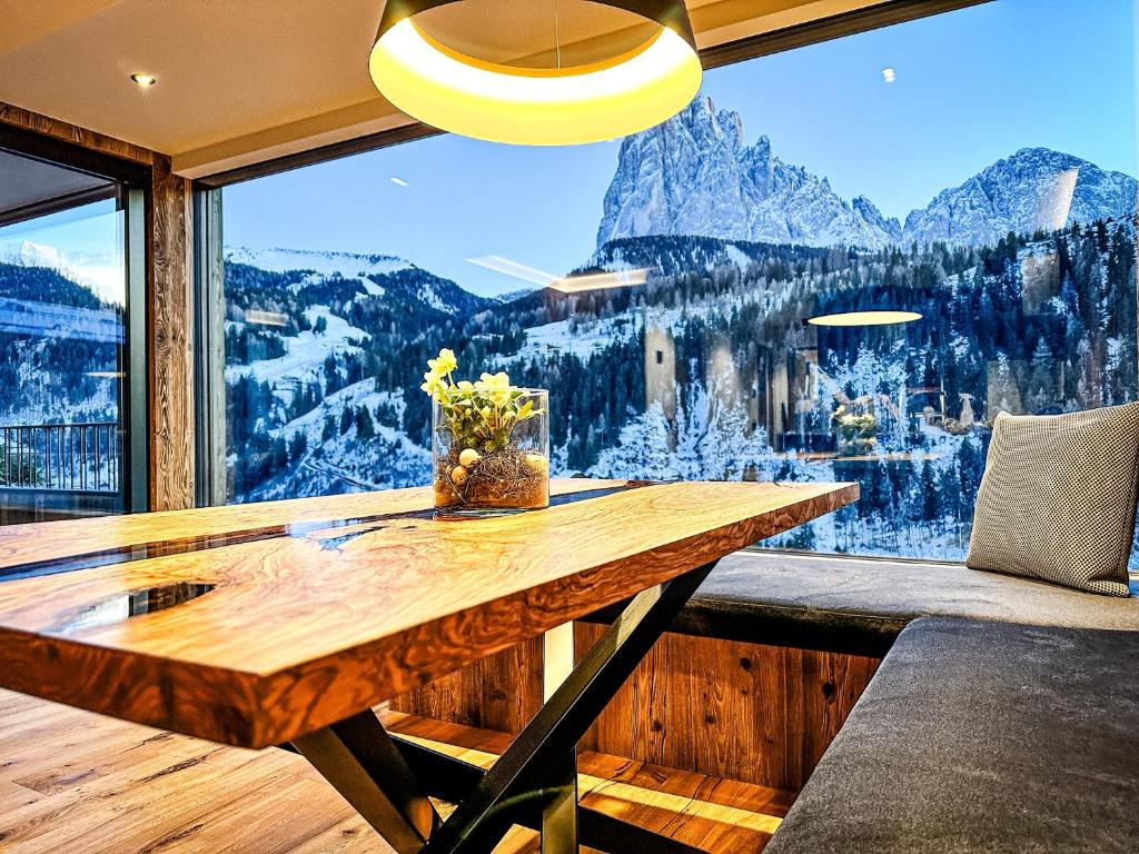 圣克里斯蒂娜Enjoy Dolomites - Chalet的配有大窗户的客房内的木桌