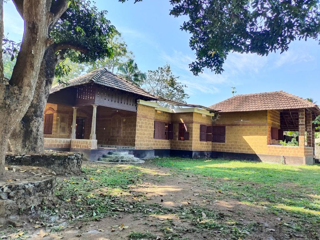 KodaliChithira Homestay (Kerala traditional mud house)的前面有一棵树的老房子