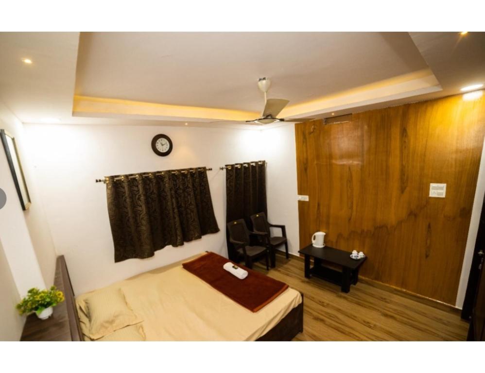 贾巴尔普尔Bisman Lodge, Jabalpur的一间卧室配有一张床、一张桌子和闹钟