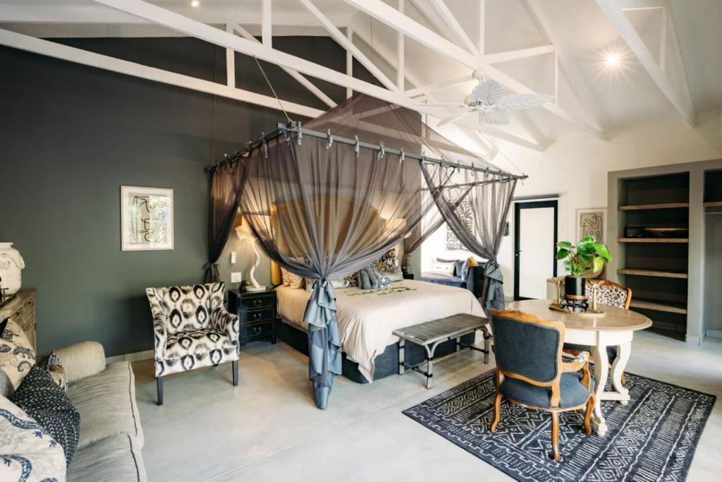 侯斯普瑞特Safari Moon Luxury Bush Lodge的卧室配有一张床和一张桌子及椅子