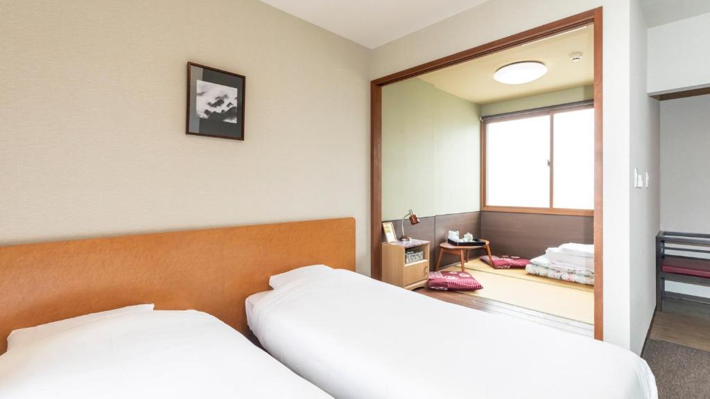 米子市Tabist International Hotel Kaike的一间卧室配有两张床和镜子