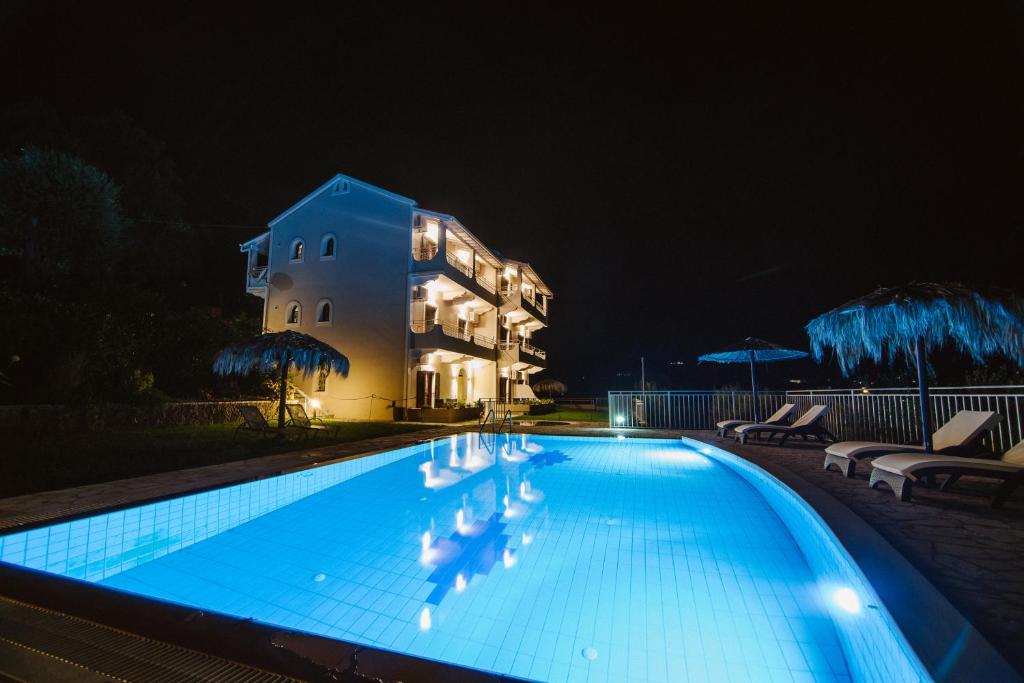 达西亚Giorgos apartments的一座游泳池,在晚上在建筑物前
