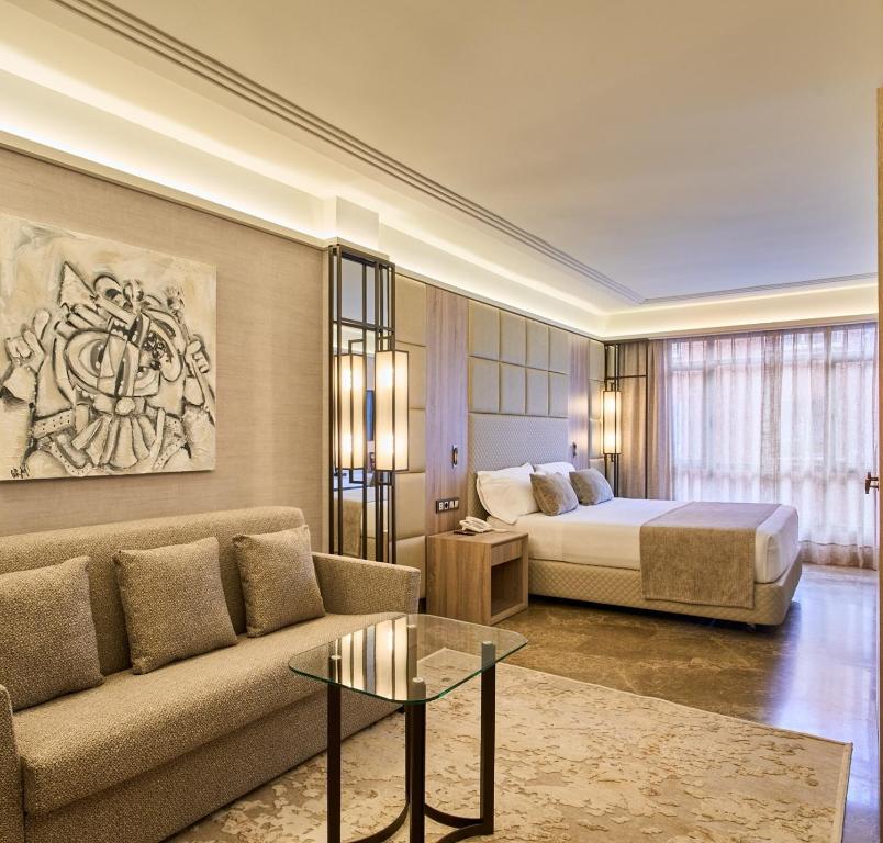 马德里VP Madroño的酒店客房配有床、沙发和桌子。