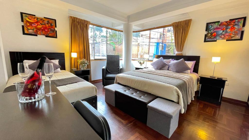 库斯科Allincay Cusco Apart Hotel的酒店客房带两张床和一张桌子以及椅子。
