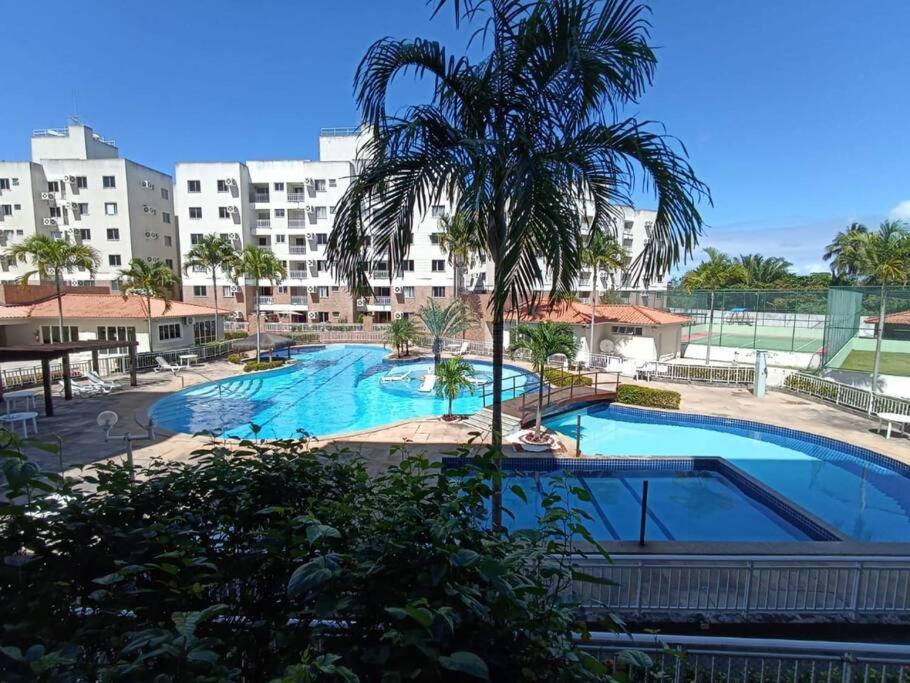 阿拉卡茹Apartamento Clube 3/4 com Ar-condicionado的一座大型游泳池,在一座建筑前方有一棵棕榈树