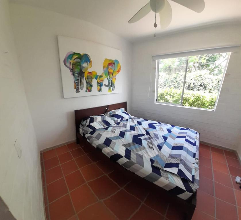 圣菲德安蒂奥基亚Querido Palmar的一间卧室配有一张带五颜六色的被子的床和窗户
