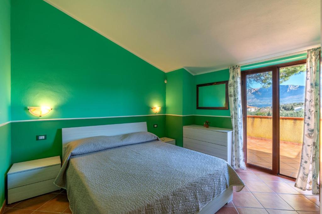 特拉佩托Casa Delle Pomelie的绿色卧室设有床和窗户
