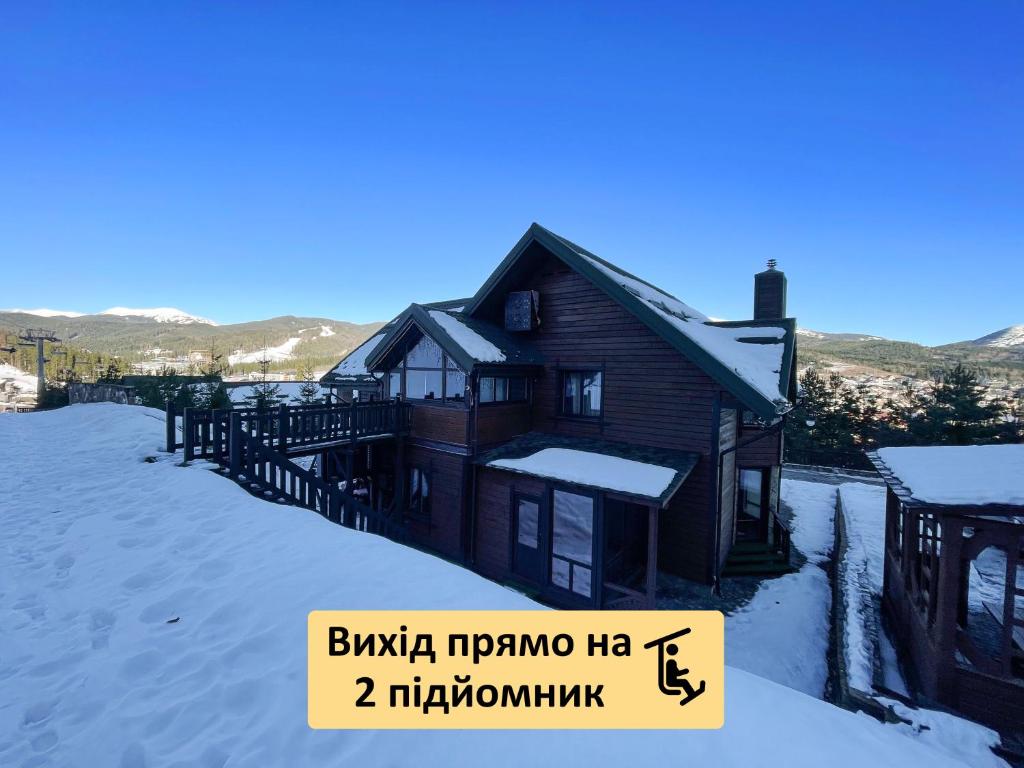 布克维Nordian chalet next to Bukovel ski lift的雪中的房子,前面有标志