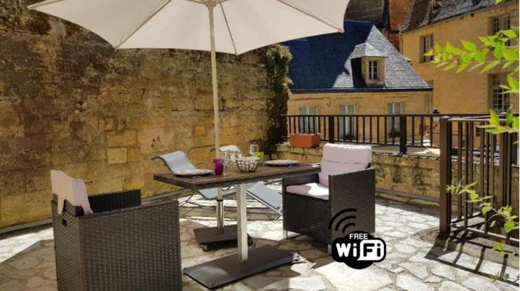 萨尔拉拉卡内达L'Appartement du "Coup de Coeur de Sarlat"的阳台上配有带雨伞的桌子