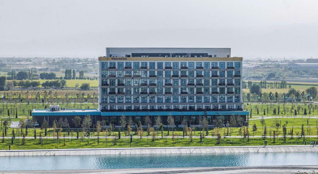 撒马尔罕Hilton Garden Inn Samarkand Sogd的一座大型建筑,前面有湖泊