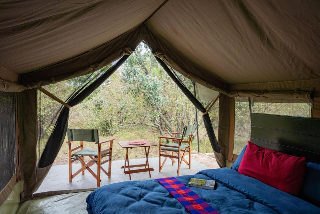 Mara SimbaOlimba Mara Camp的帐篷内的卧室配有桌椅