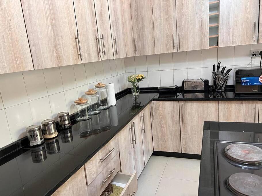 KitweFour m luxury Apartment.的厨房配有木制橱柜和黑色台面