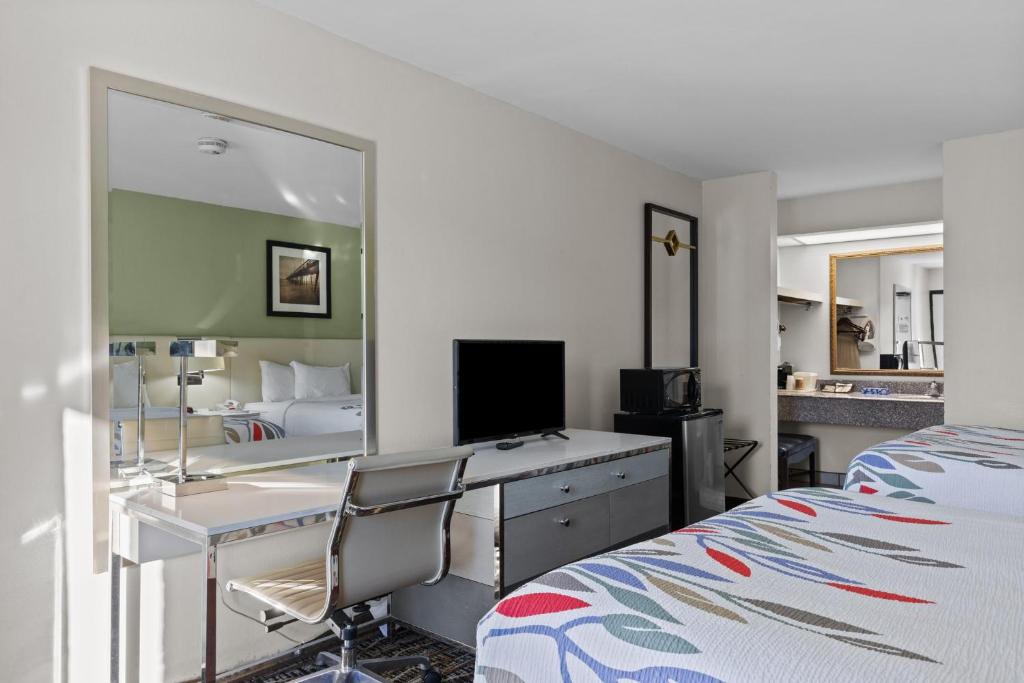 莫尔黑德城Garnet Inn & Suites, Morehead City near Atlantic Beach的一间卧室配有书桌、一张床和镜子