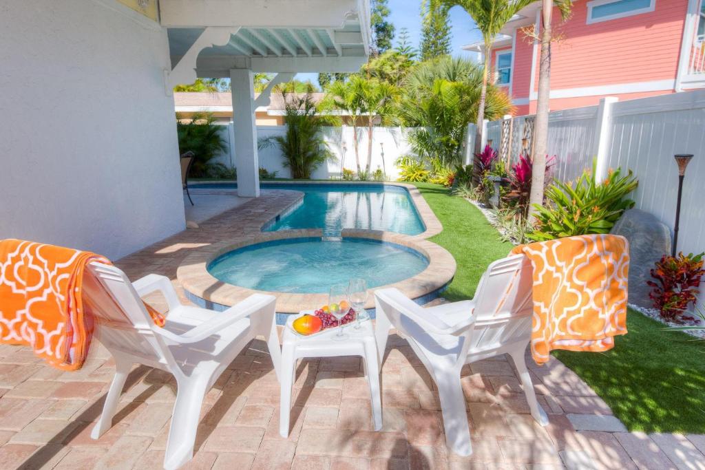 霍姆斯海滩Pineapple Key的一个带两把椅子和一张桌子的庭院和一个游泳池
