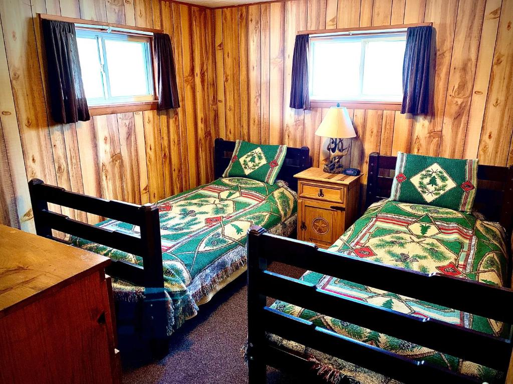 BenzoniaBenzonia Rustic Resort的一间卧室设有两张床、一张桌子和两个窗户。