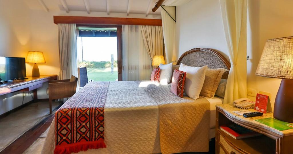科曼达图巴岛Transamerica Comandatuba - All Inclusive Resort的一间卧室配有一张带书桌和电视的床。
