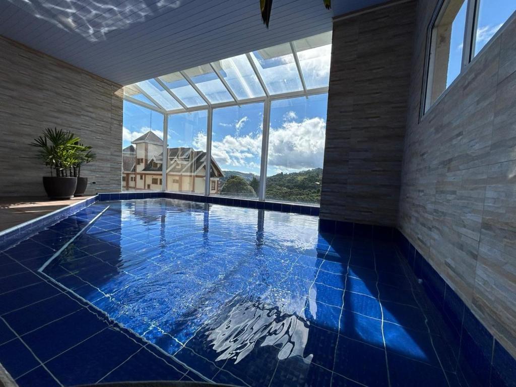 坎波斯杜若尔当Pousada Kaliman Luxo的一座带大窗户的房屋内的游泳池