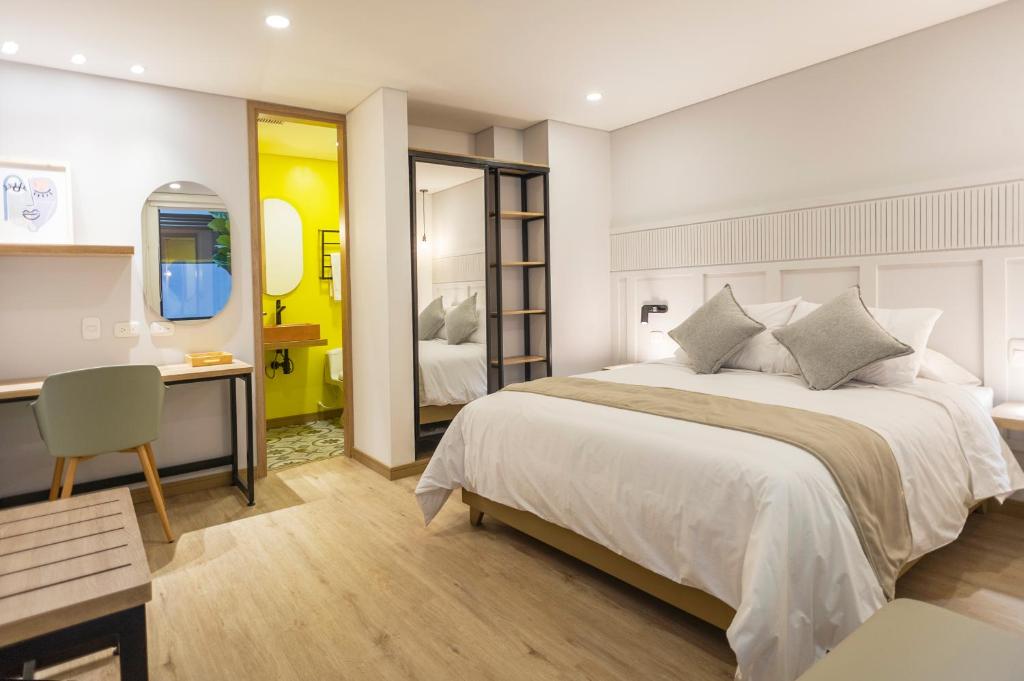 帕斯托Siete Balcones Hotel y Coworking的一间卧室配有一张床、一张书桌和一面镜子