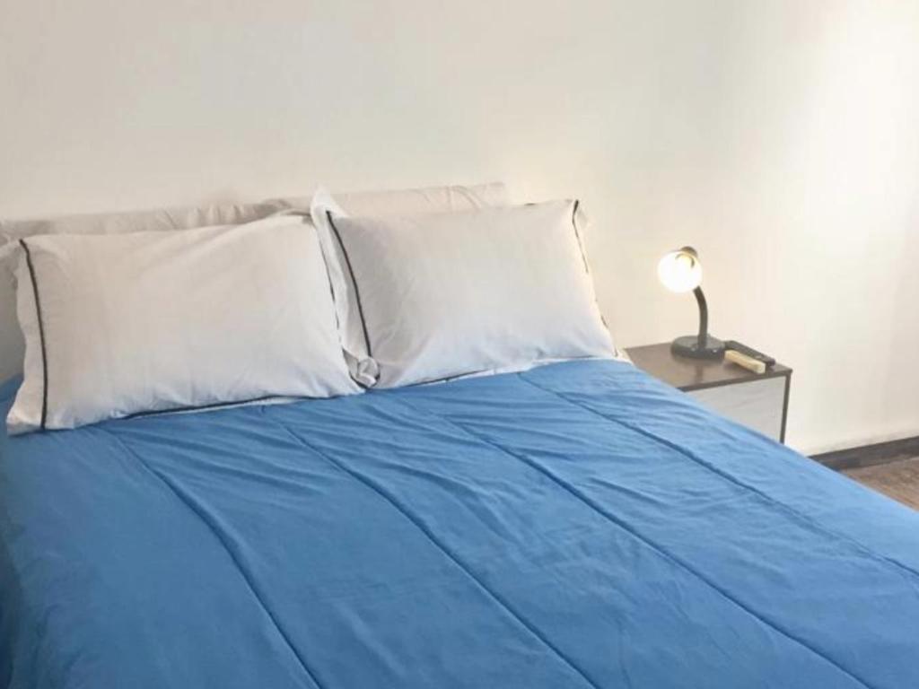 蒙得维的亚Artistes du Monde的一张带白色枕头的蓝色床和一张带台灯的桌子