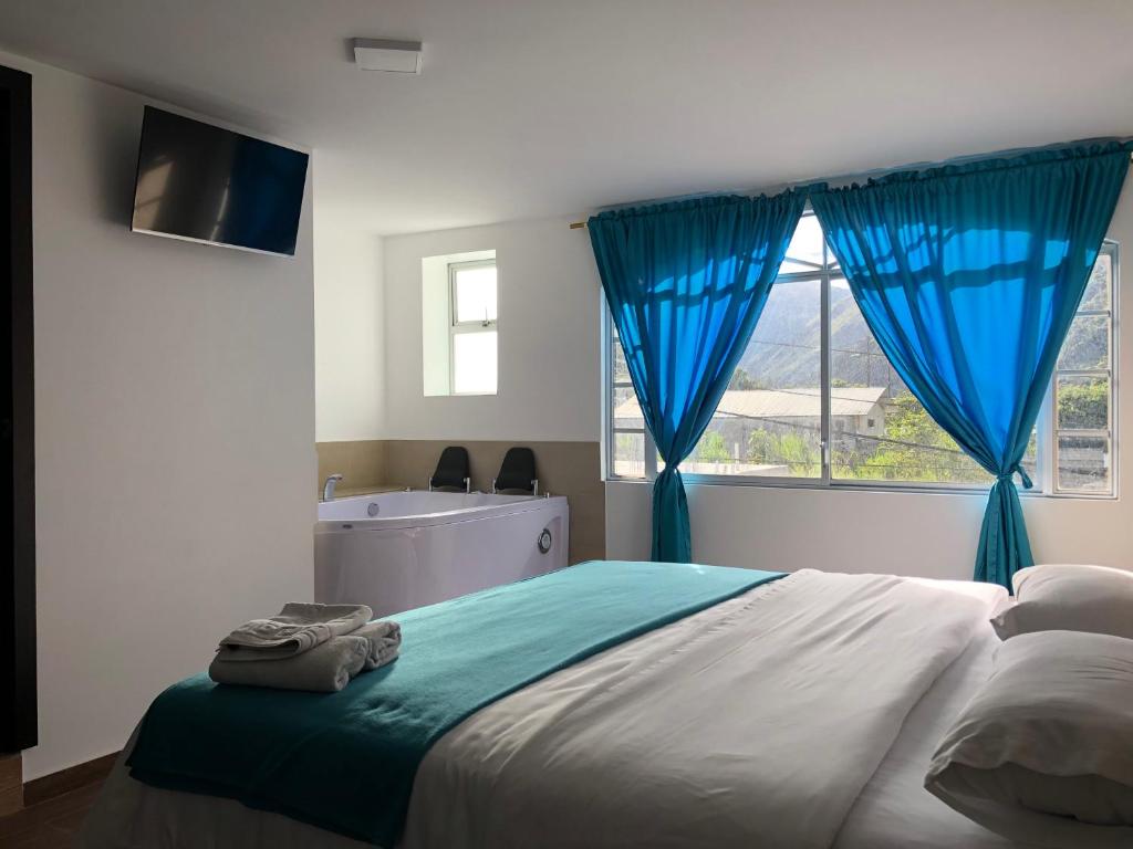 巴尼奥斯First Class Hotel en Baños - Ciudad Volcan的一间卧室配有一张带蓝色窗帘的床和一扇窗户