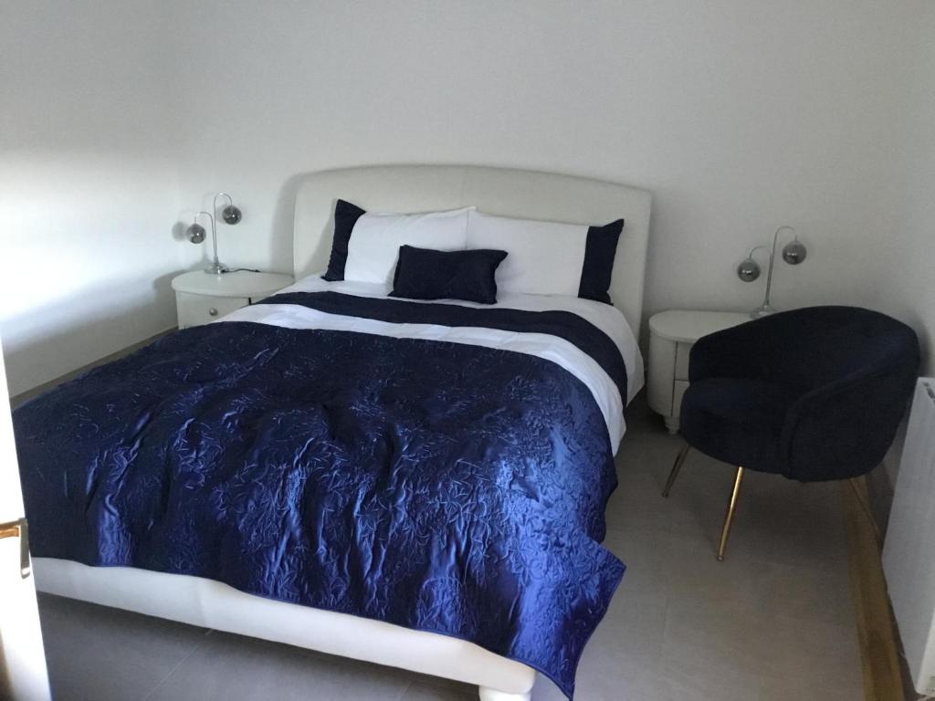 BroadfordCosy Cottage Broadford的一间卧室配有一张带蓝色被子和椅子的床