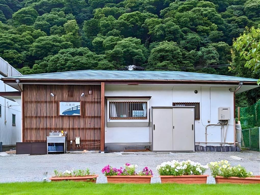 箱根箱根湯本 川風荘 - Hakone Yumoto Kawakazesou的前面有鲜花的小房子