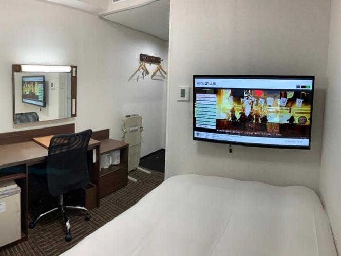上越市Hotel Alpha-One Joetsu的酒店客房配有一张床、一张书桌和一台电视。