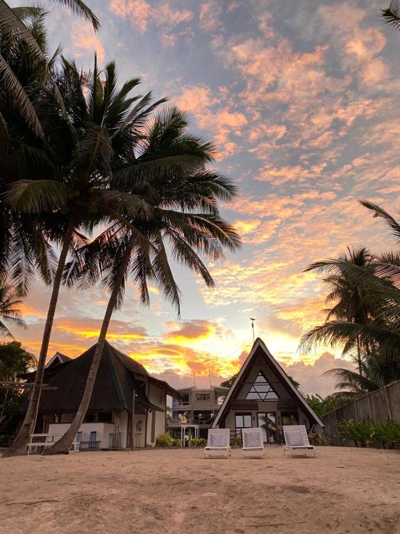AborlanSurya Beach Resort Palawan的两棵棕榈树和一座建筑的海滩