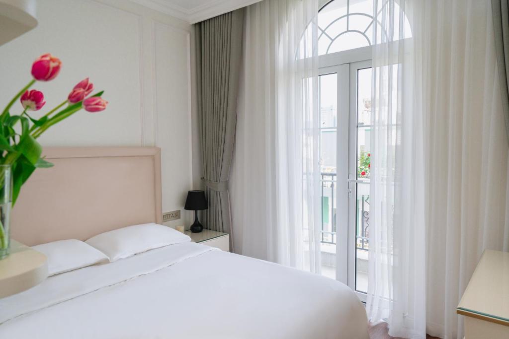 胡志明市The Nguyens - Pink Church View的卧室配有白色的床和粉红色花卉窗户。