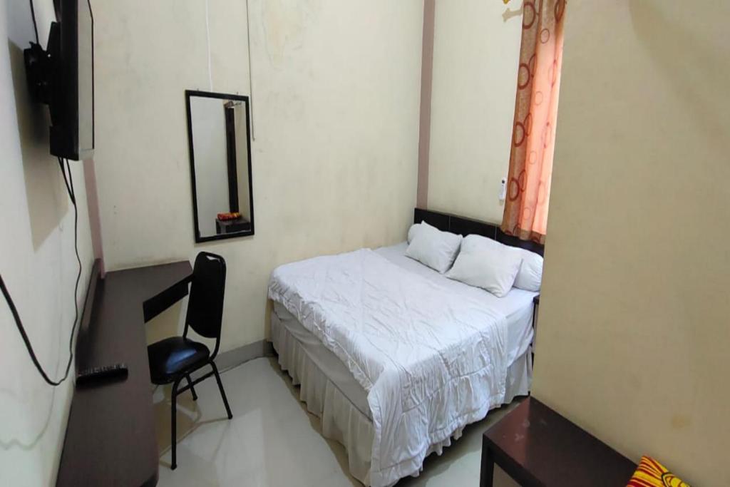 查亚普拉OYO 93479 Hotel Jaguar Sentani的一间小卧室,配有一张床和一把椅子