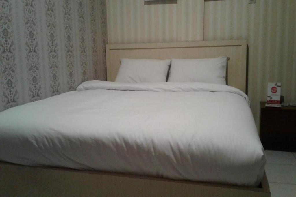 查亚普拉OYO 93485 Hotel Kenzie Sentani的一张配有白色床单和枕头的大床