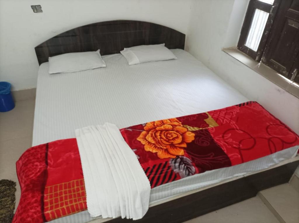 RaxaulHotel Dharam Mukti Utsav Bhawan (DMUB)的床上有红白毯子