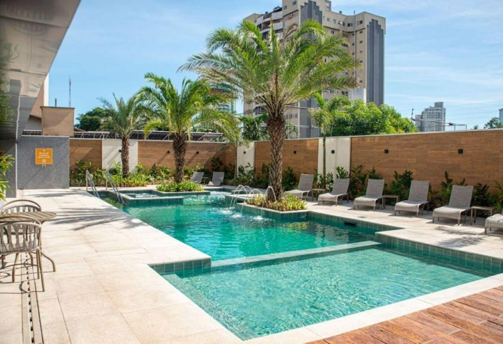 伊瓜苏拉费恩中心酒店的一座带椅子和棕榈树的游泳池