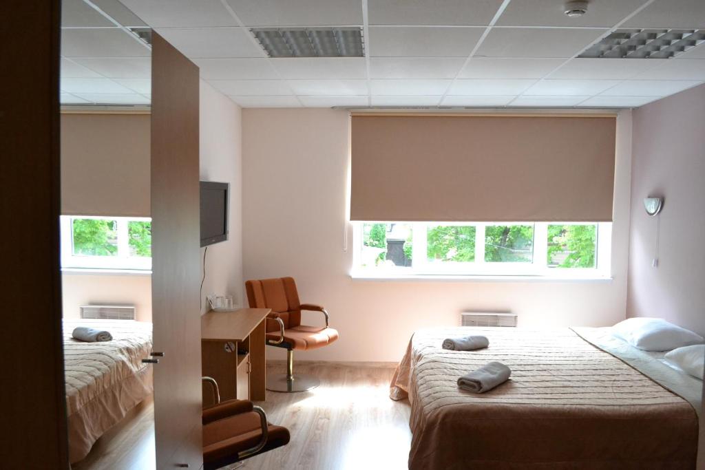 派尔努Villa Katariina的一间卧室配有两张床、一张桌子和两个窗户。