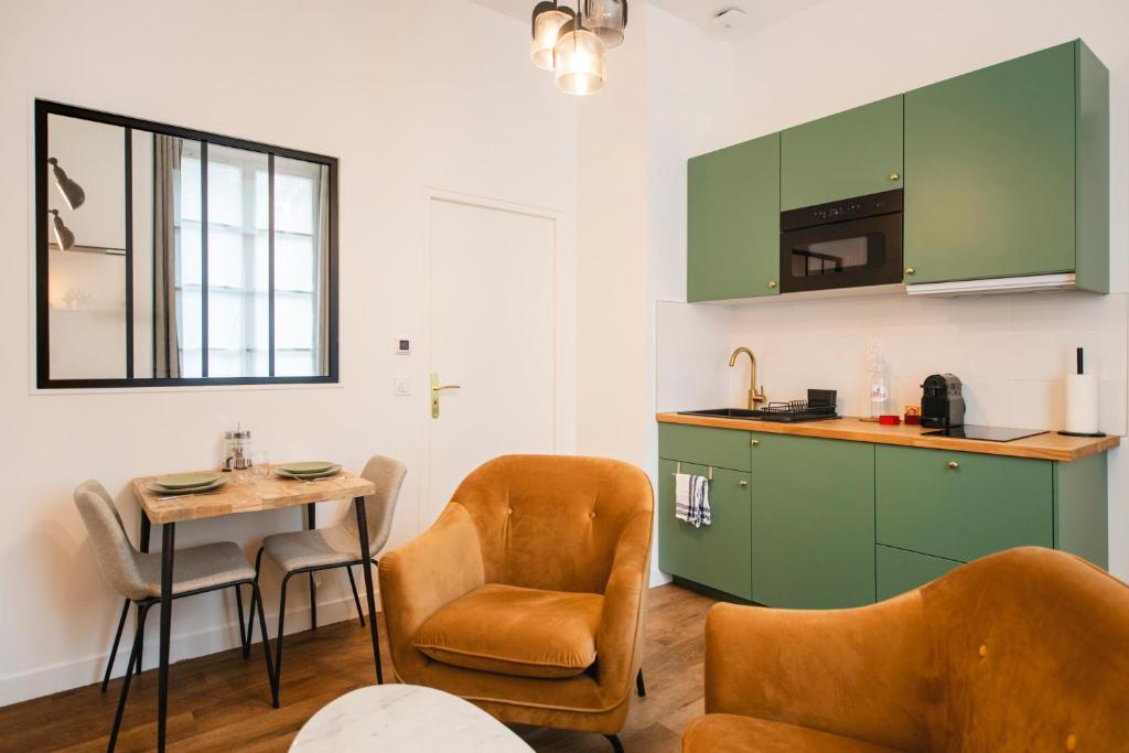 桑斯Le Laurencin Sens - Le Keys的厨房配有绿色橱柜和桌椅