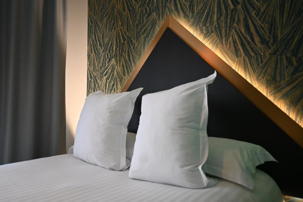 敦刻尔克LOGIS Hôtel Borel的一张带白色枕头和木制床头板的床