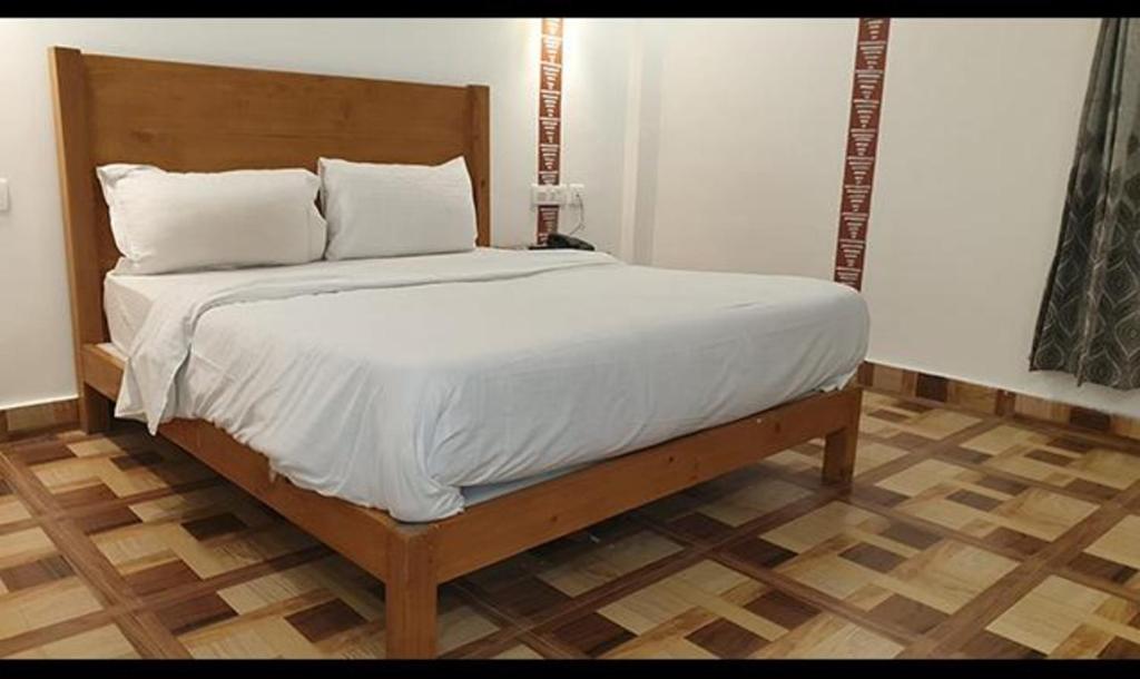 穆索里FabHotel Rudraksh Resort的一张带白色床单和枕头的床