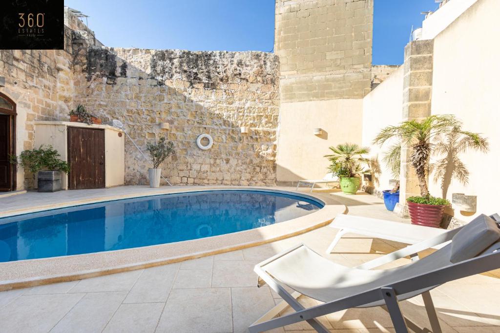 ŻebbuġA stunning, townhouse with magnificent pool area by 360 Estates的一座游泳池,旁边是一座建筑,配有椅子