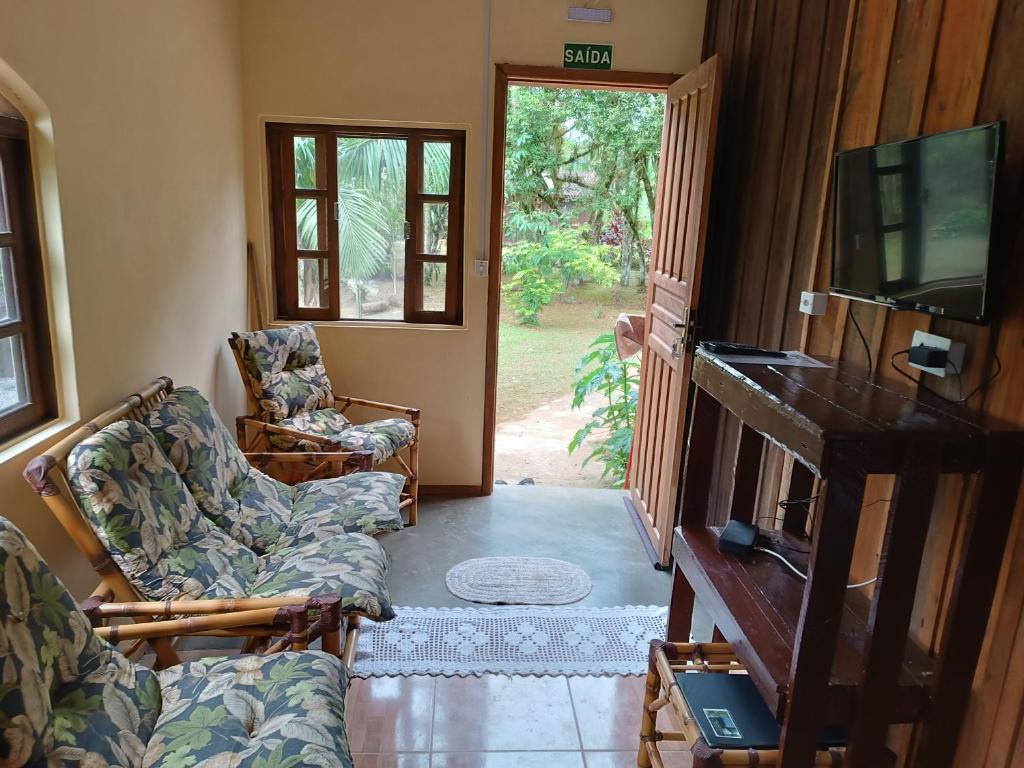莫雷蒂斯Pousada Serra Verde Ecolodges的客厅配有两把椅子、电视和门