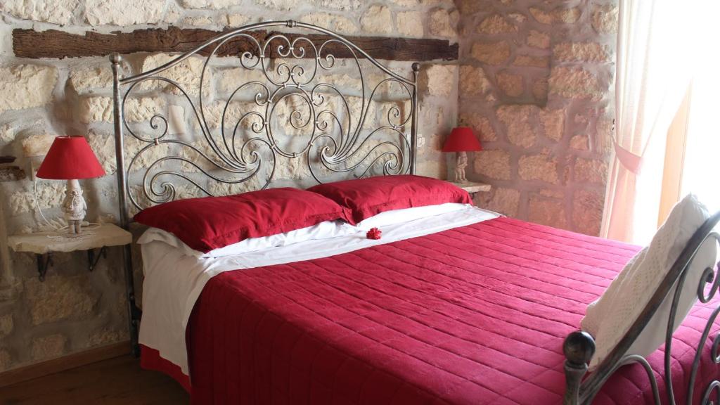 Pennapiedimonte罗诺莫住宿加早餐旅馆的卧室内的一张带红色床单和红色枕头的床