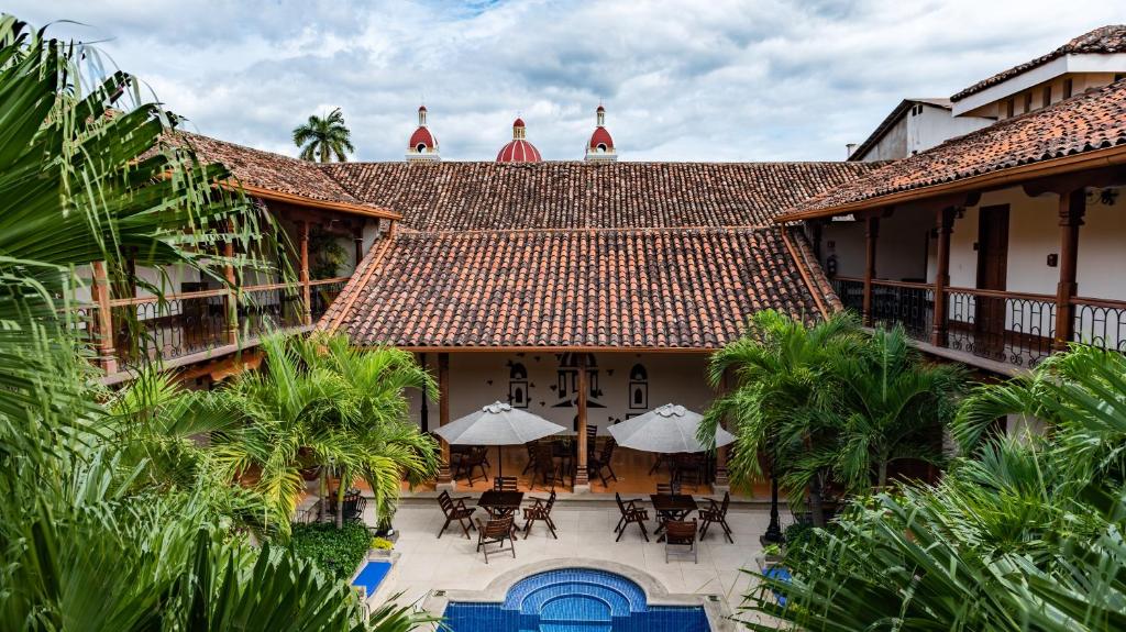 格拉纳达Hotel Plaza Colon - Granada Nicaragua的享有大楼空中美景,配有桌子和伞