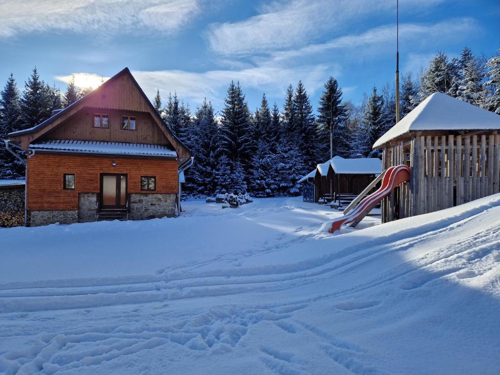 温佩尔克Šumavská Barborka的一座带雪盖的院子,里面设有一座房子和滑梯