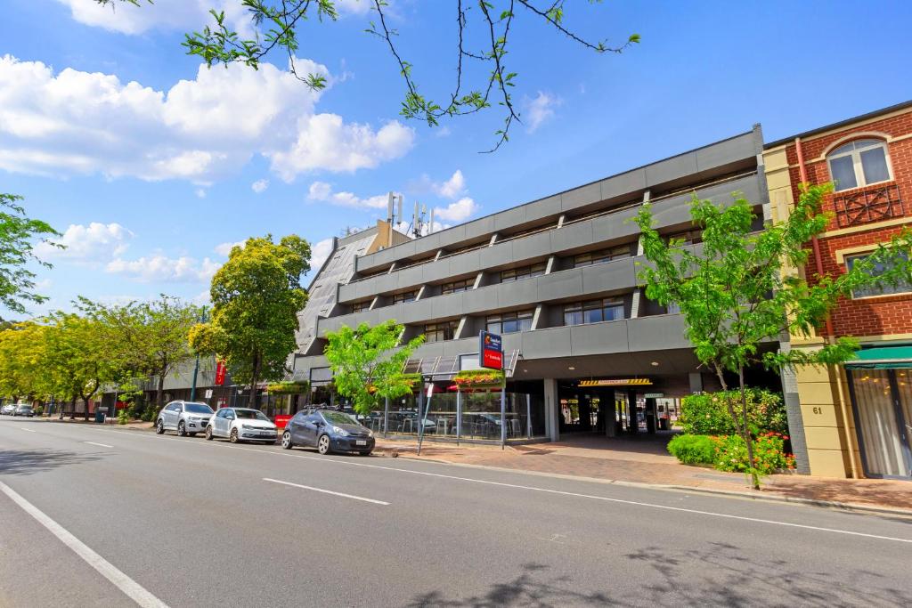 阿德莱德Comfort Hotel Adelaide Meridien的一条在大楼前停放汽车的街道