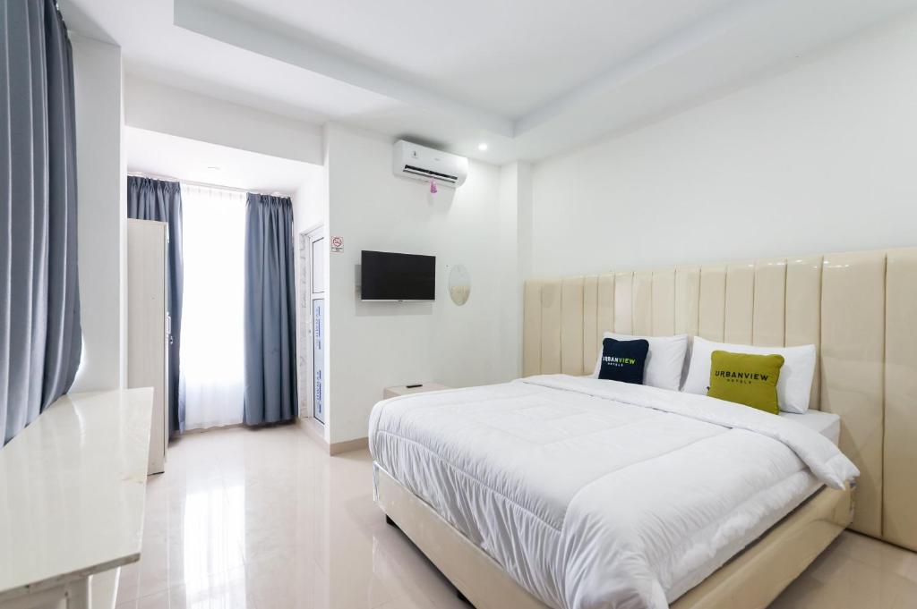 班达亚齐Urbanview Hotel Ranls Dream Banda Aceh by RedDoorz的一间白色卧室,配有一张大床和一台电视